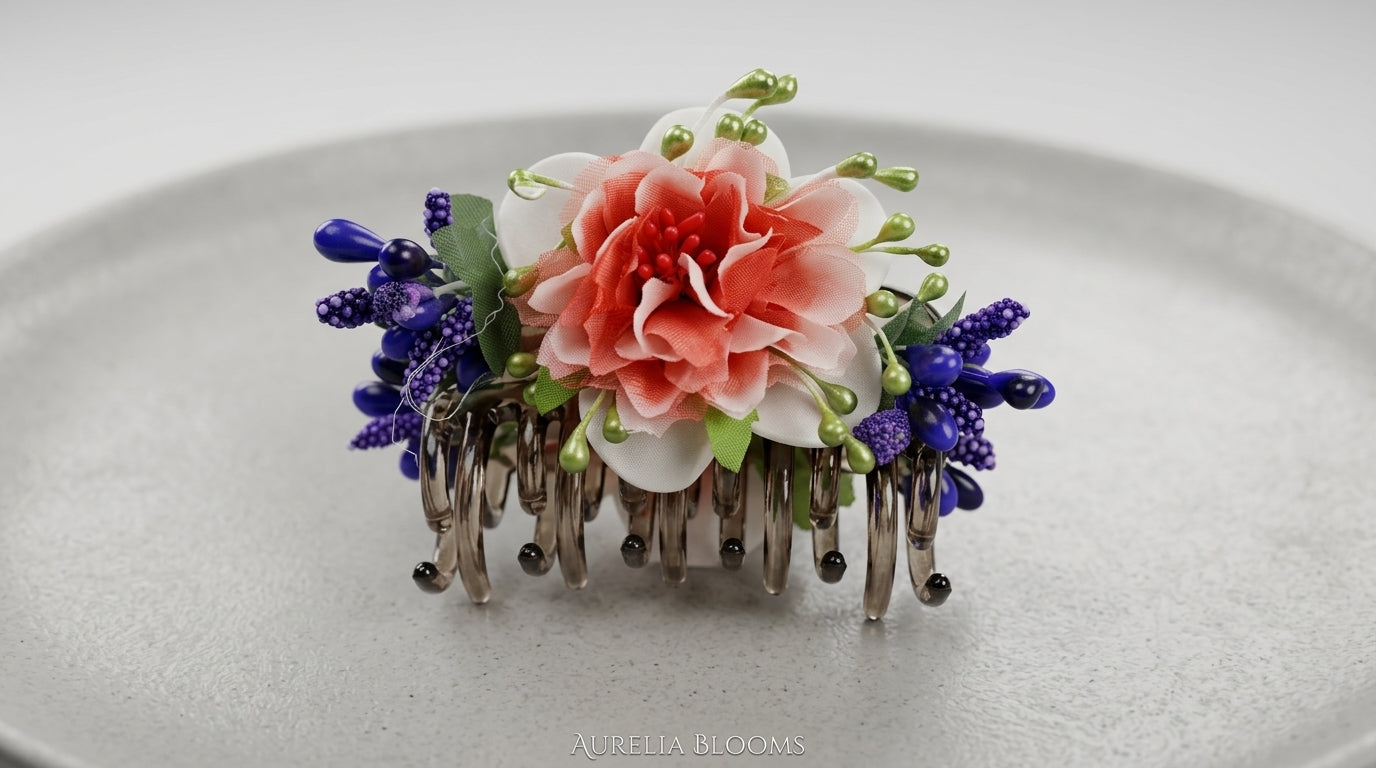 Floral silver metal hair comb clip with coral peony centre, white magnolia petals, cobalt blue berry clusters and green pearl stamens on ceramic plate